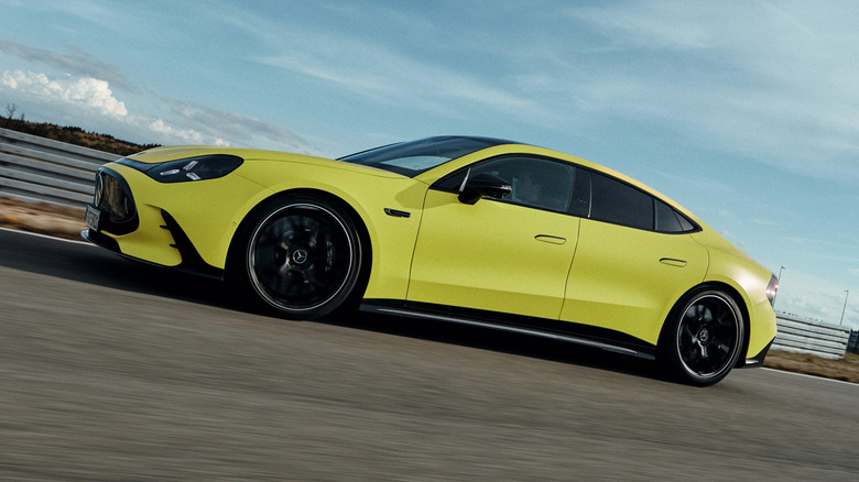 Side view of a yellow 2027 Mercedes-AMG GT 4-Door Coupe EV driving on track
