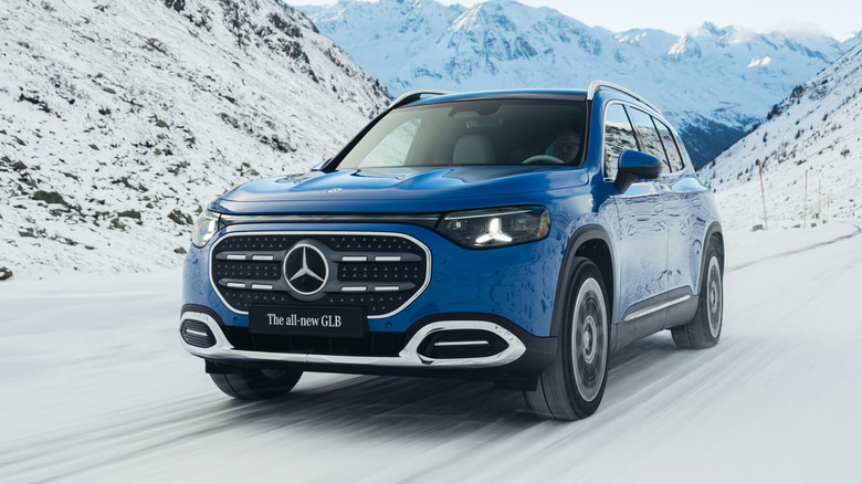 Front 3/4 view of a blue 2027 Mercedes-Benz GLB driving in snow