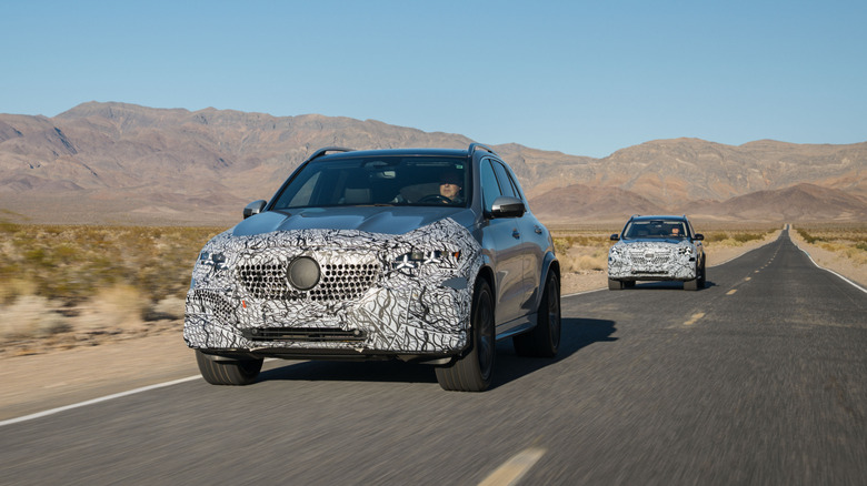 Two camouflaged Mercedes-Benz SUVs driving in the desert