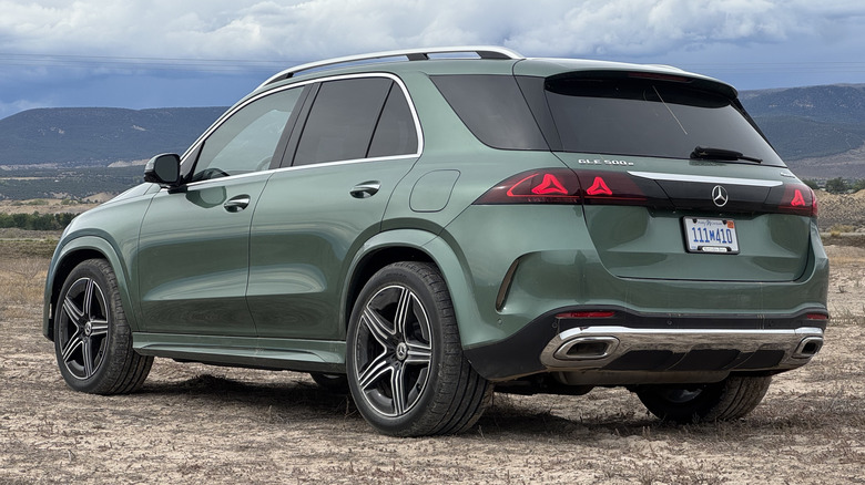 A rear three-quarters shot of a green GLE500e parked on dirt in front of a view of a cloudy sky