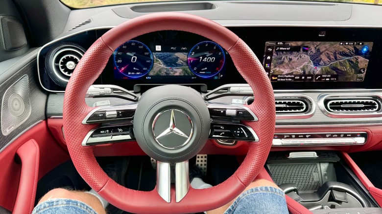 A photo from my POV in the driver's seat of the GLE580 with its red leather interior and both the driver's display and the infotainment screen visible