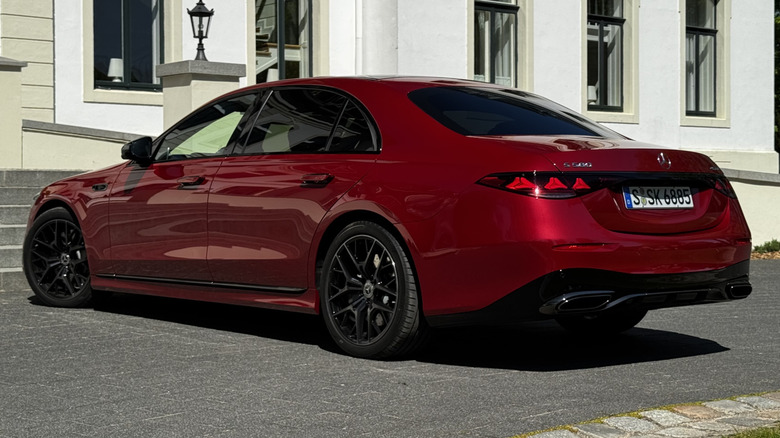 A rear three-quarters shot of the red S580 parked on asphalt in front of a white building
