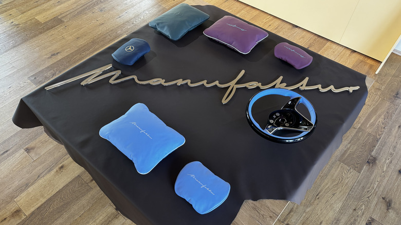 A top-down photo of a table with different colored interior pillows and a steering wheel to show the Manufaktur Made To Measure program