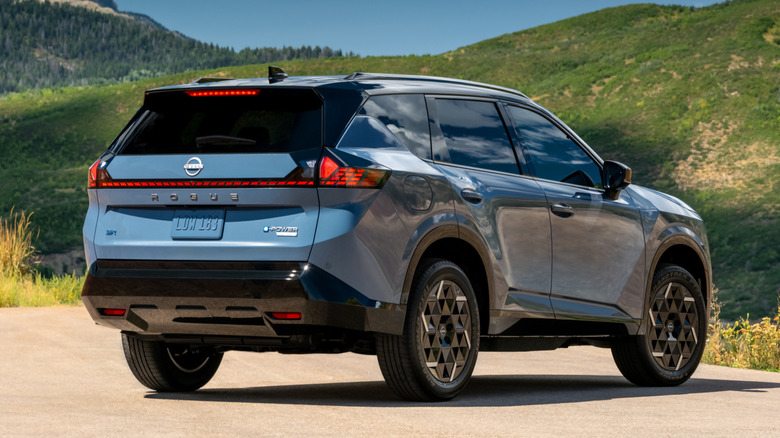 Rear 3/4 view of a blue 2027 Nissan Rogue Hybrid