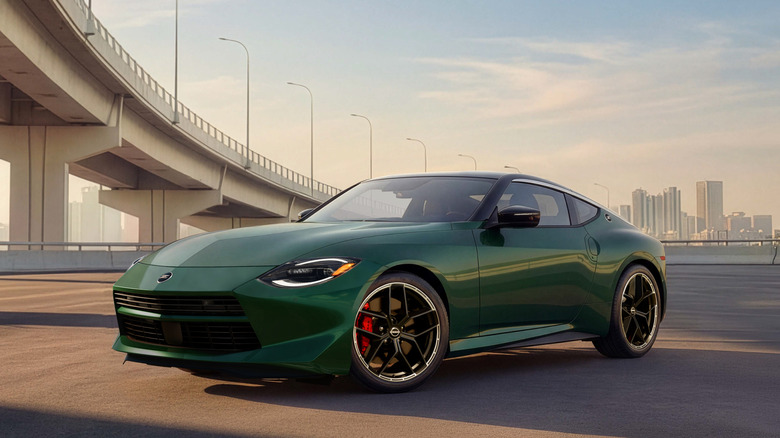 A front three-quarters shot of a green Z parked under a bridge in front of a cityscape at sunset