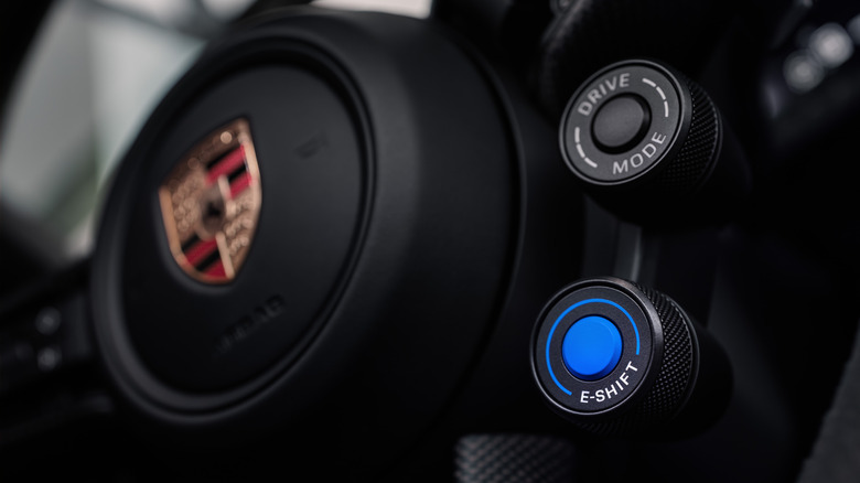 A close-up of the new blue E-Shift toggle on the Taycan's steering wheel, just below the drive mode wheel