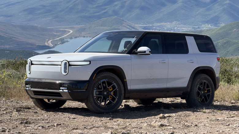 Front 3/4 view of a white 2027 Rivian R2 in front of mountains