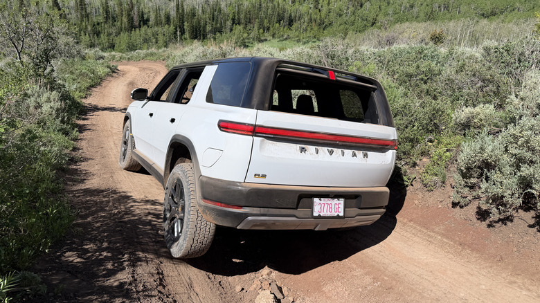 Rear 3/4 view of a white Rivian R2 on an off-road trail