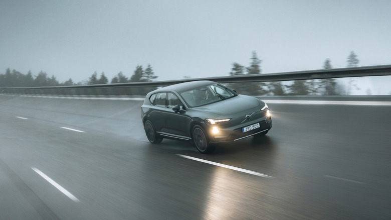 A dark green Volvo EX60 driving on a banked turn