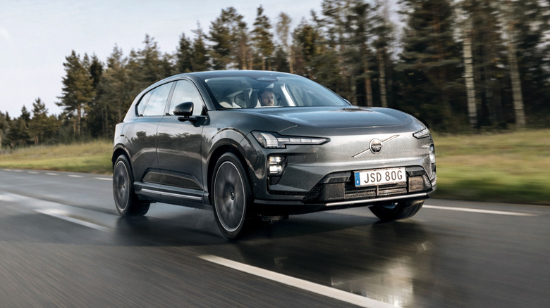 A dark gray Volvo EX60 driving down a two-lane road