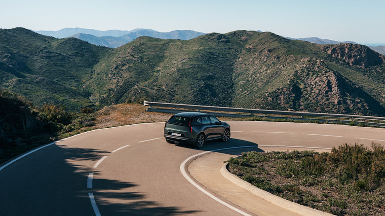 A dark green 2027 Volvo EX60 rounding a mountain hairpin