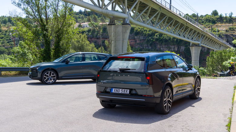 A pair of 2027 Volvo EX60s parked in the shadow of a bridge