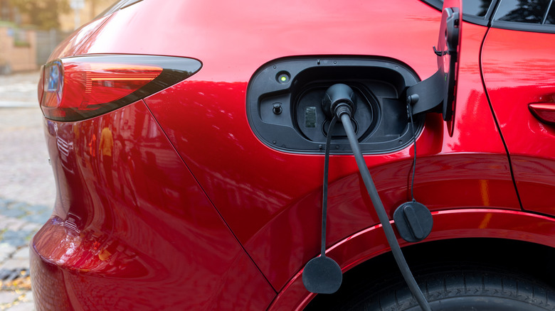A close-up of a red plug-in hybrid charging.