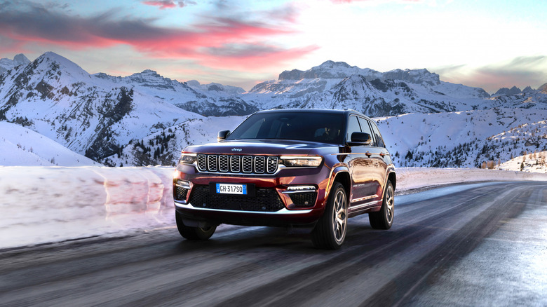 A Jeep Grand Cherokee 4xe drives through snowy mountains.