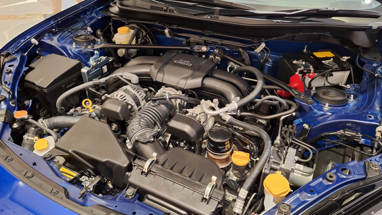 A Subaru boxer engine sitting in a blue vehicle, showing the tight quarters and complex engine bay