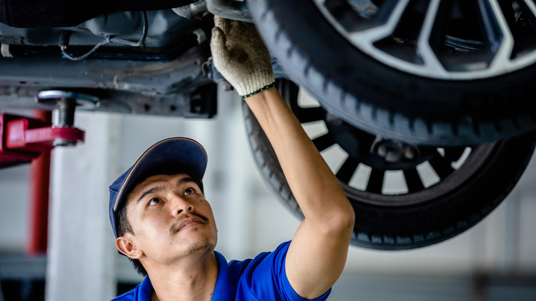 A mechanic inspecting the front underside of a car