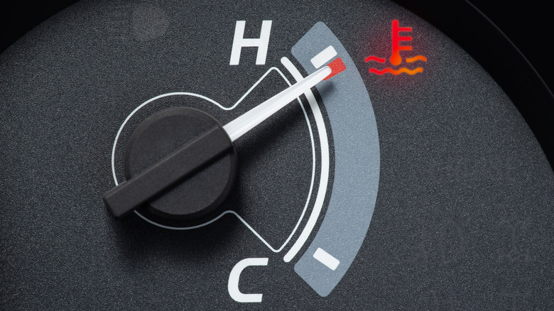 A car temperature gauge shows the needle sitting at the red end, signifying that the engine is overheating.