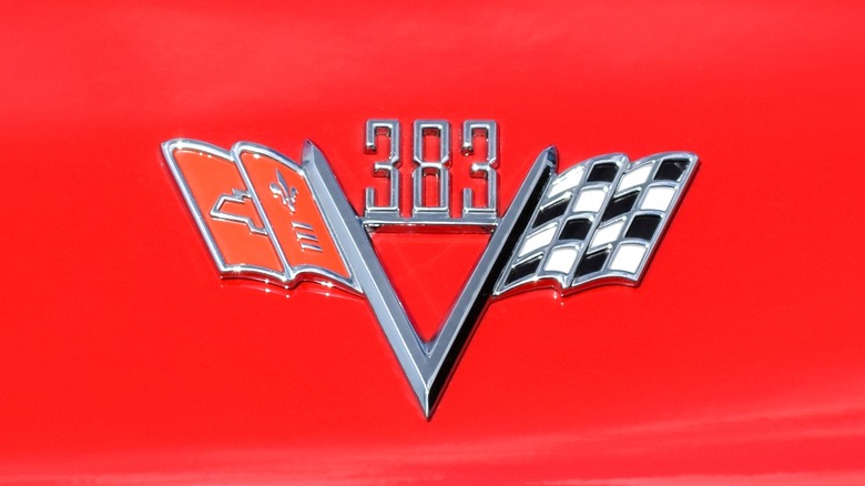 An aftermarket Chevrolet 383 logo connected a reddish pickup truck