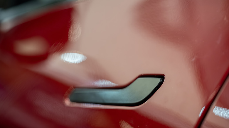 Close up of Tesla door handle on red vehicle. Toronto, Canada - February 19, 2026.