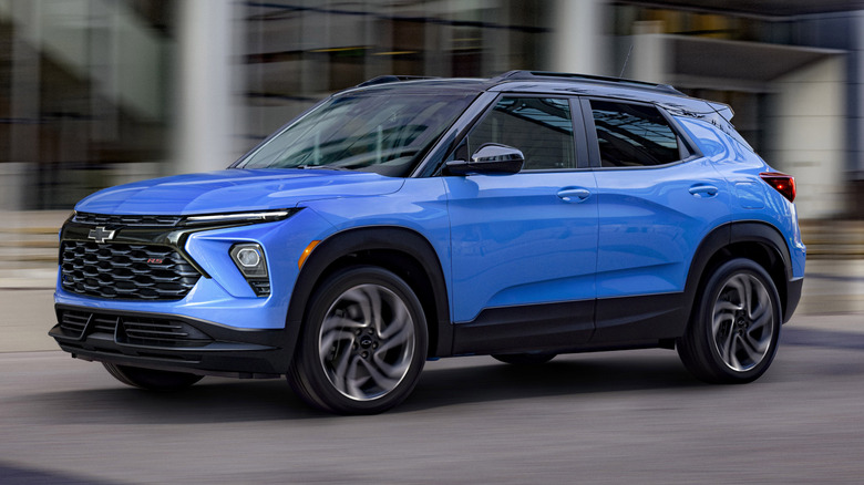The front 3/4 view of a Fountain Blue Chevrolet Trailblazer RS driving in front of a building