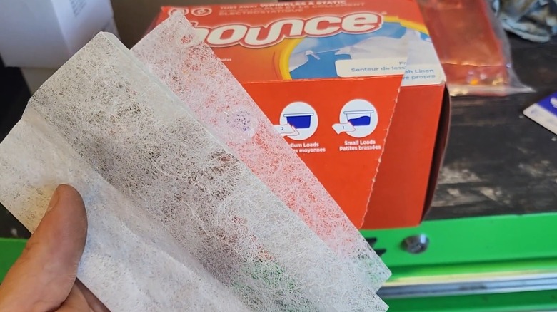 A man holding a dryer sheet with a bounce box in the background