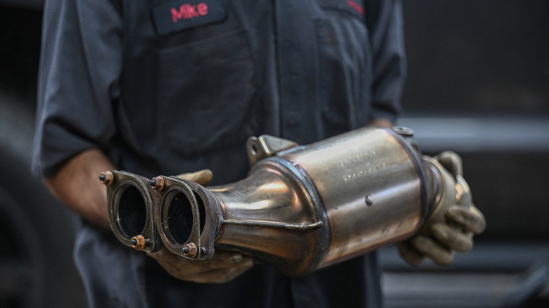 A mechanic holding a catalytic converter