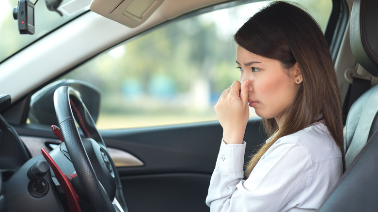 A woman in smelly car holding her nose