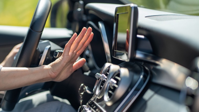 A car driver feeling the air coming from the dash vents.
