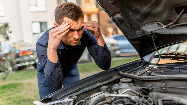 Concerned man looking at his car's engine