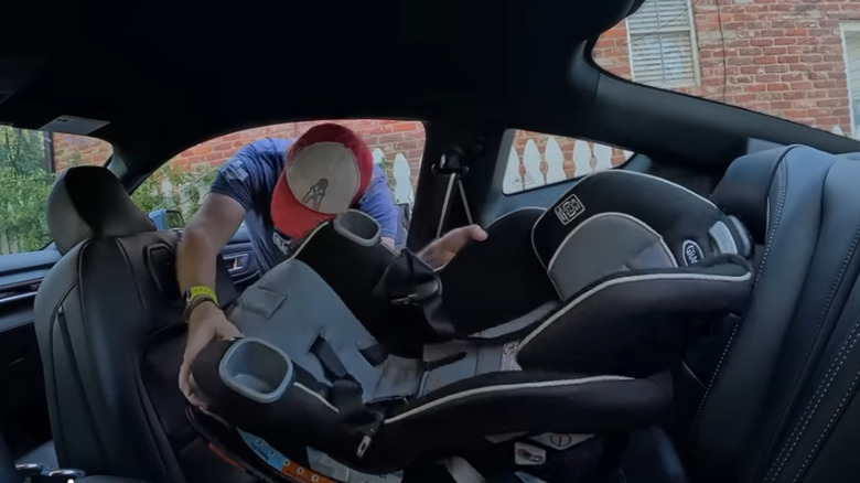 Man putting front-facing child seat in the rear of a 2025 Ford Mustang GT