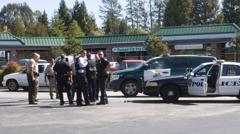 Police force gathered together near pet stores, surrounded by both police and civilian vehicles