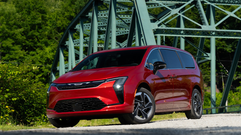 A red 2027 Chrysler Pacifica parked in front of a bridge.