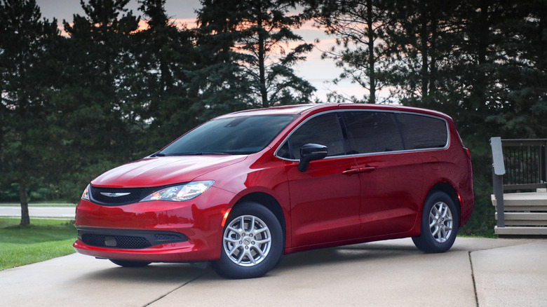 A red 2026 Chrysler Voyager parked next to steps and in front of trees.
