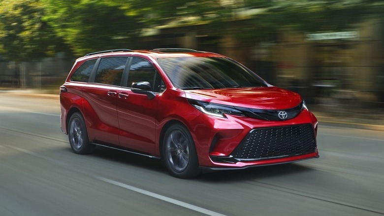 A red 2026 Toyota Sienna in motion with trees and buildings in the background.
