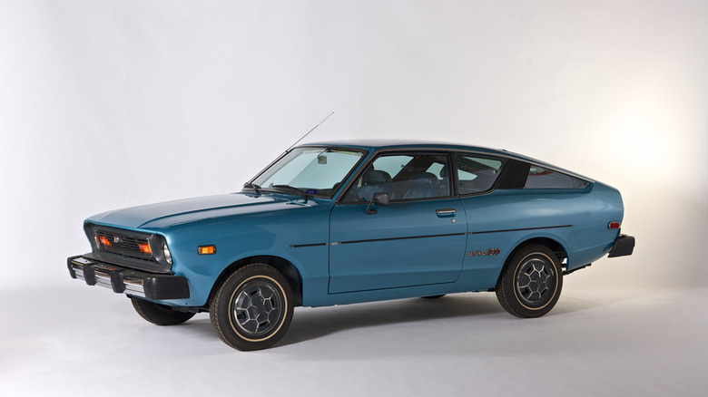 A light blue metallic 1970s Datsun B210 fastback hatchback coupe isolated against a plain white background.