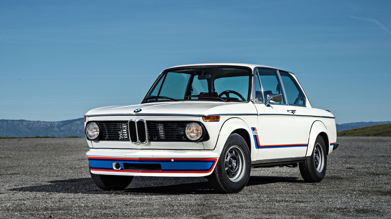 A pristine white BMW 2002 Turbo displaying its front air dam, flared wheel arches, and classic round grille outside