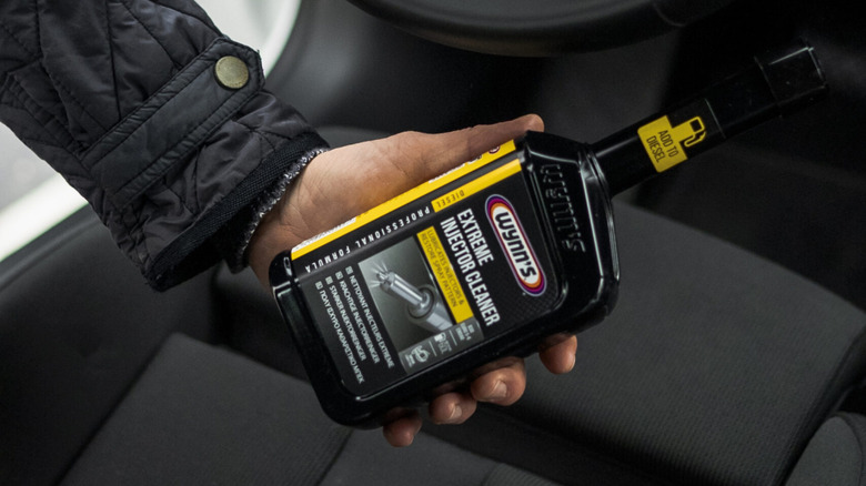 a person holding a bottle of Wynn's Extreme Diesel Cleaner