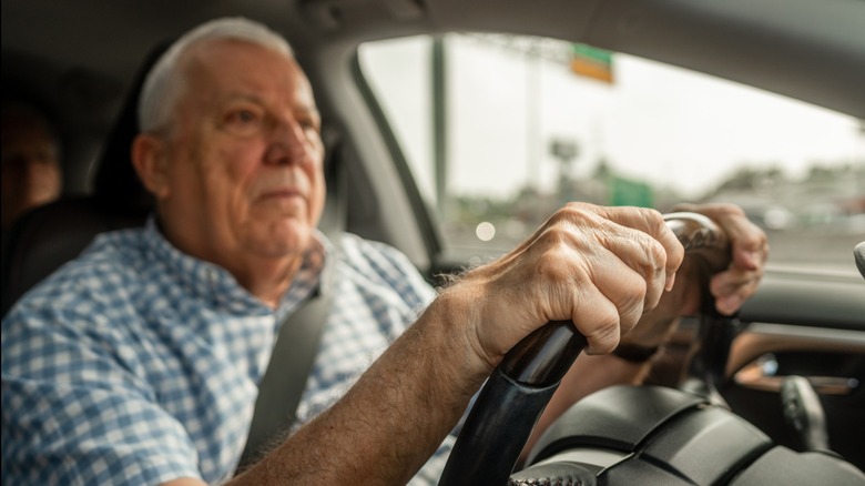 Older man gripping steering wheel