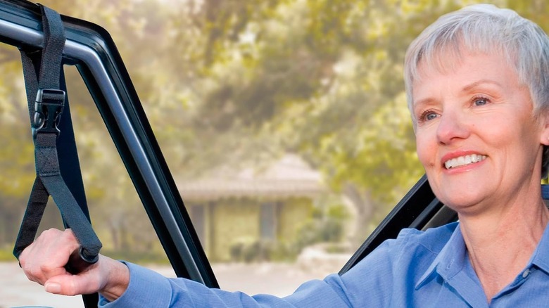 An elderly female driver using a Stander CarCaddie Car Safety Grab Bar