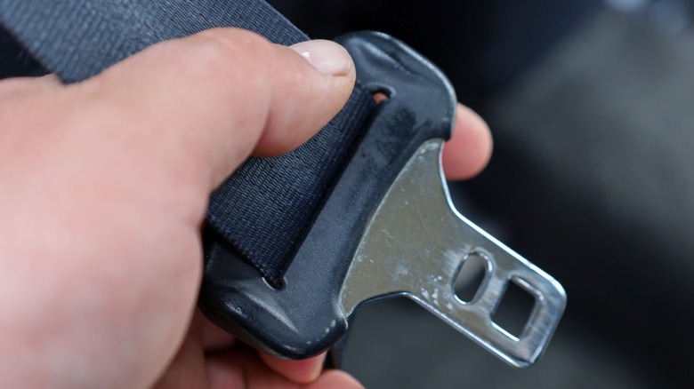 Close-up of a hand holding a seat belt buckle.