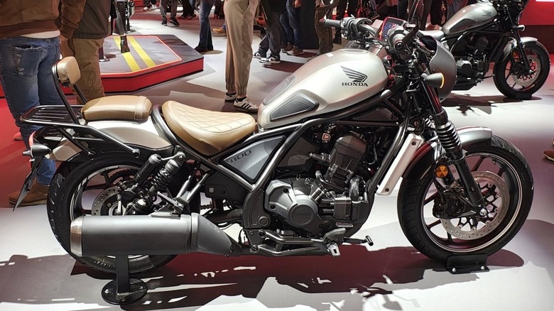 A black and white Honda Rebel inside at a Motorcycle show, with people and other bikes in the background