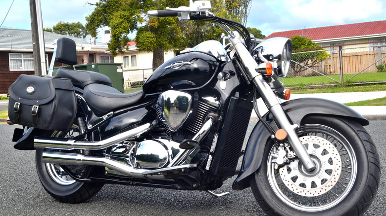 A Black Suzuki Boulevard C50 parked on a suburban street with one-story houses in the background
