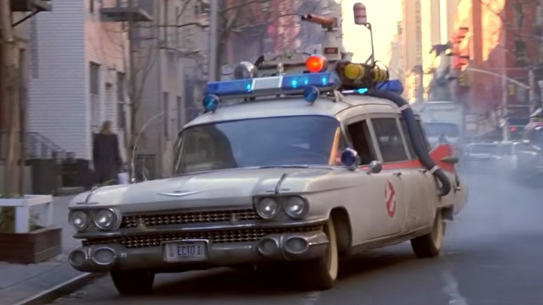 A still from the movie Ghostbusters showing the Ecto-1 on a city street