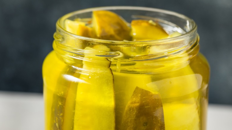 An opened jar of dill pickles.