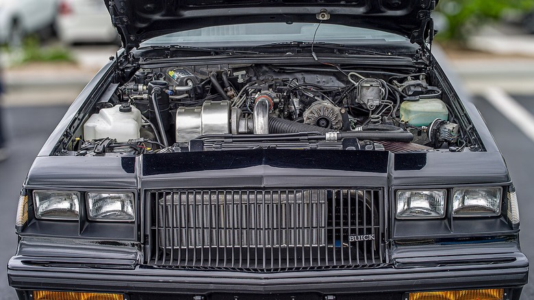 A black 1987 Buick Regal Grand National with the hood open and the turbocharged V6 engine visible.