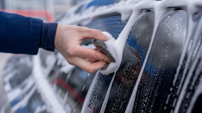 A close-up shot of a person washing a car by hand