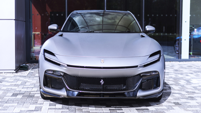 A gray Ferrari Purosangue SUV in front of a building.