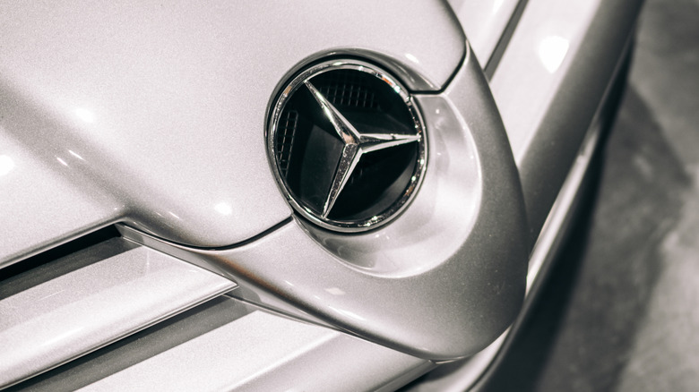 A close-up of a vintage Mercedes three-pointed star badge.