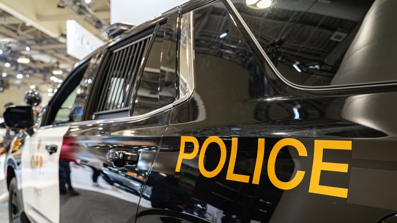 A close-up side view of a black and white police SUV with ''POLICE' written on the side.