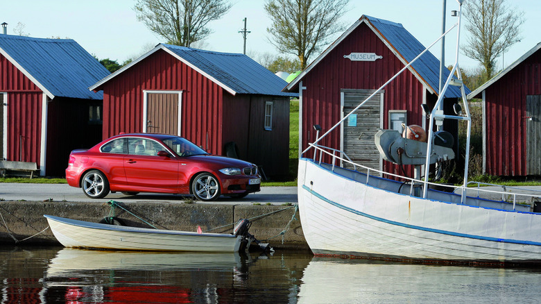 BMW 1-series coupe parked next to a boat by the water
